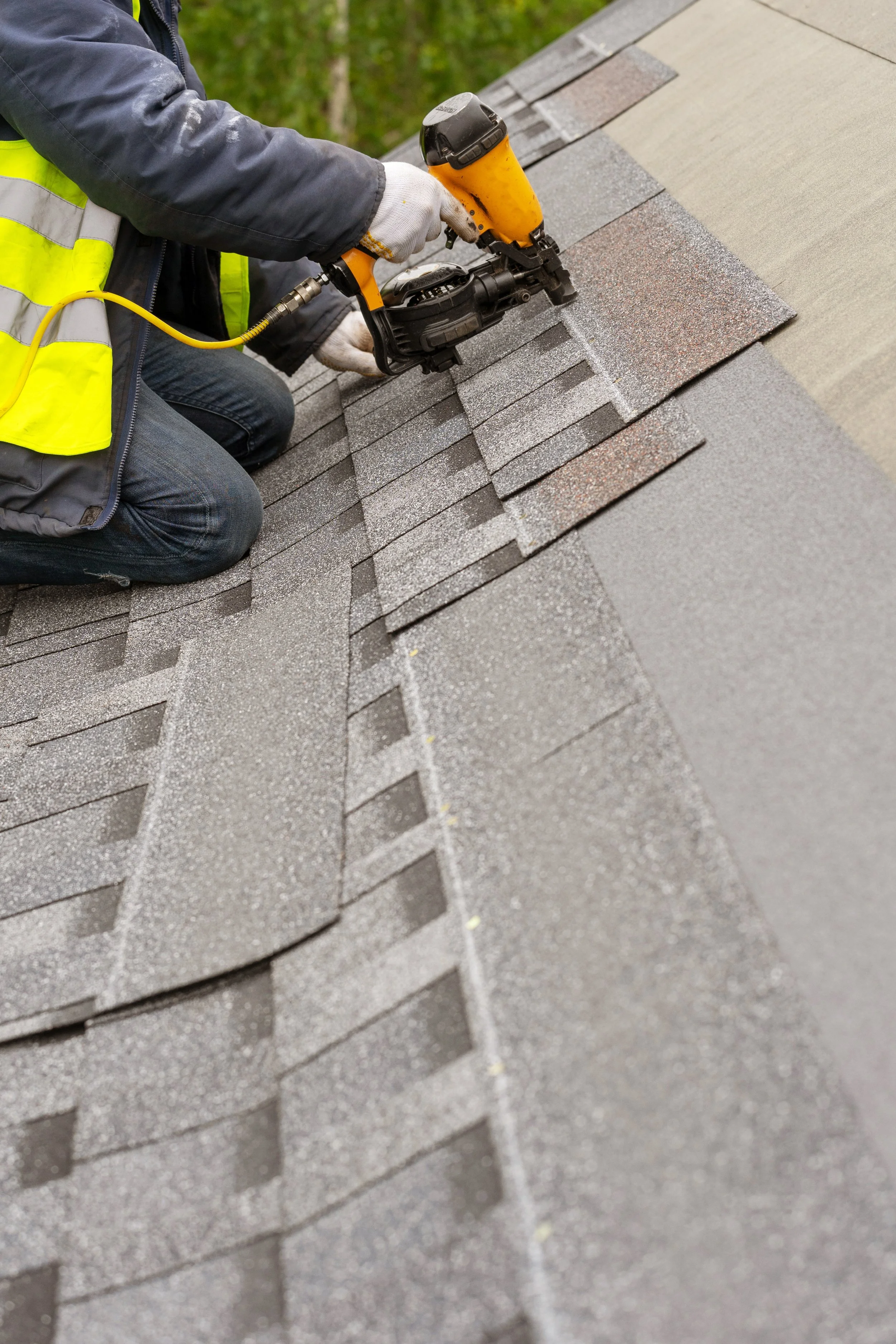 Close view of a roofer nailing shingles into place