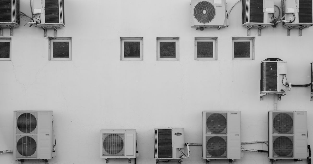 Row of air conditioning condenser units on a white wall — the kind of equipment ACpulses services in Miami Gardens
