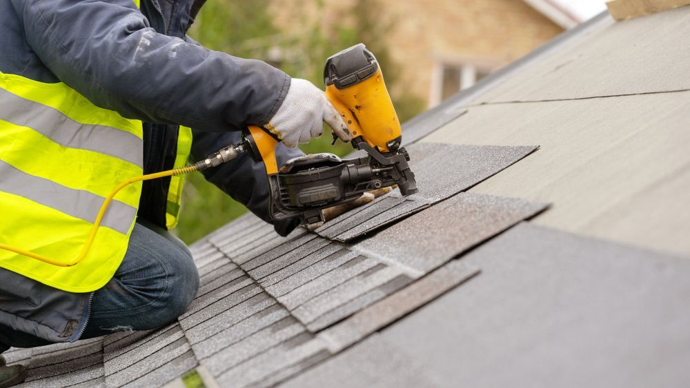 Close-up of a nail gun setting roof shingles