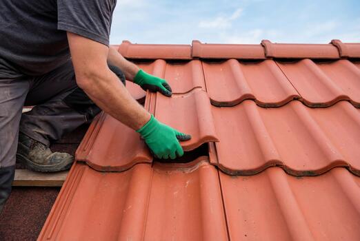 Hands setting a red clay roof tile
