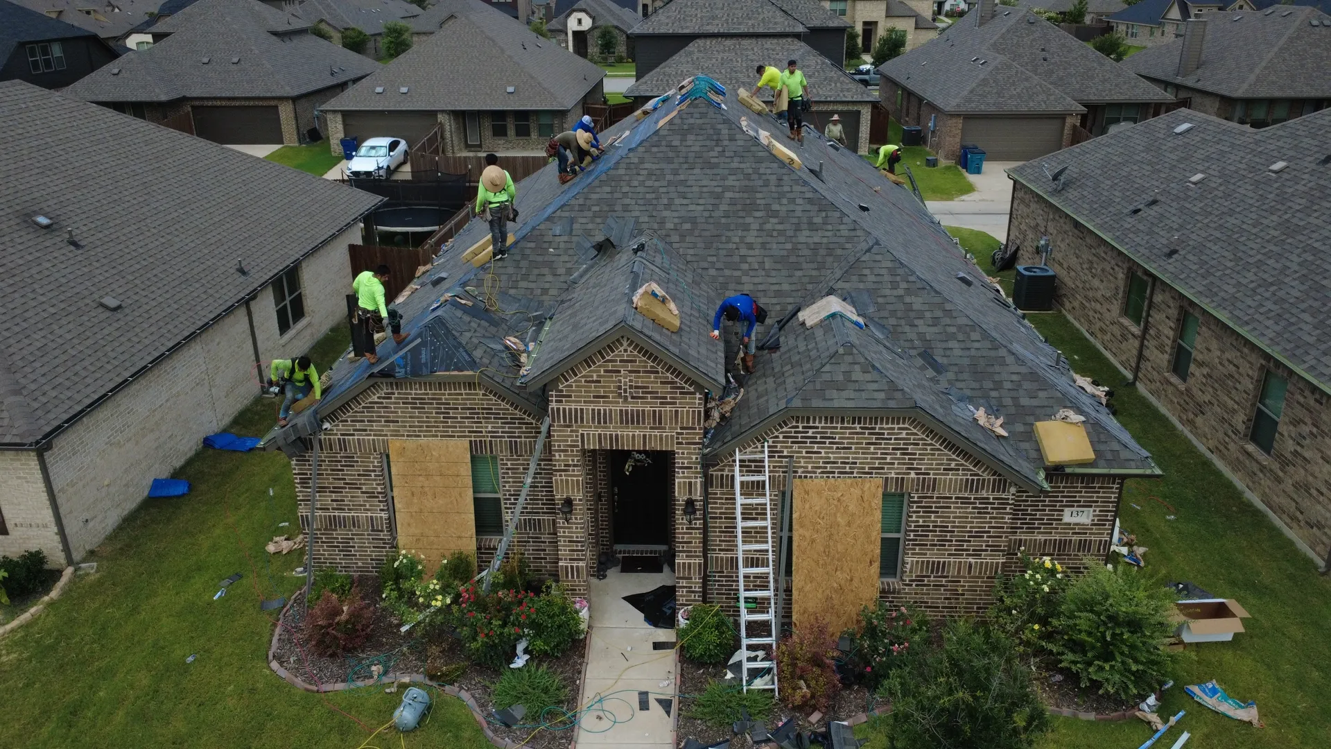 Roofing crew replacing a shingle roof, aerial view