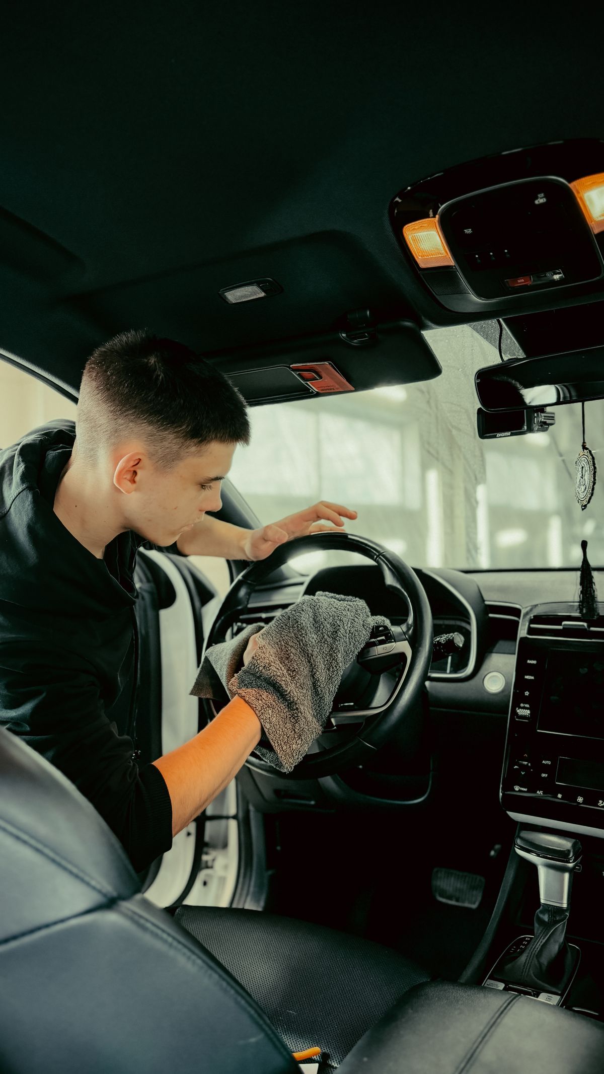 Detailer wiping a steering wheel with a microfiber cloth