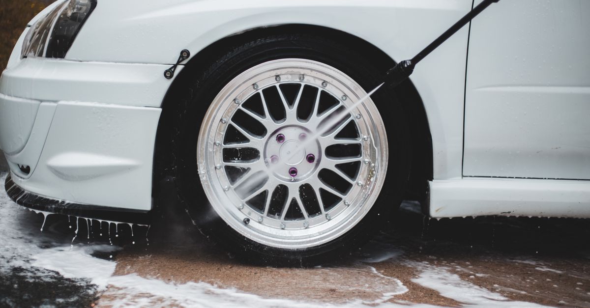 Pressure washer rinsing a mag wheel during a mobile car detail