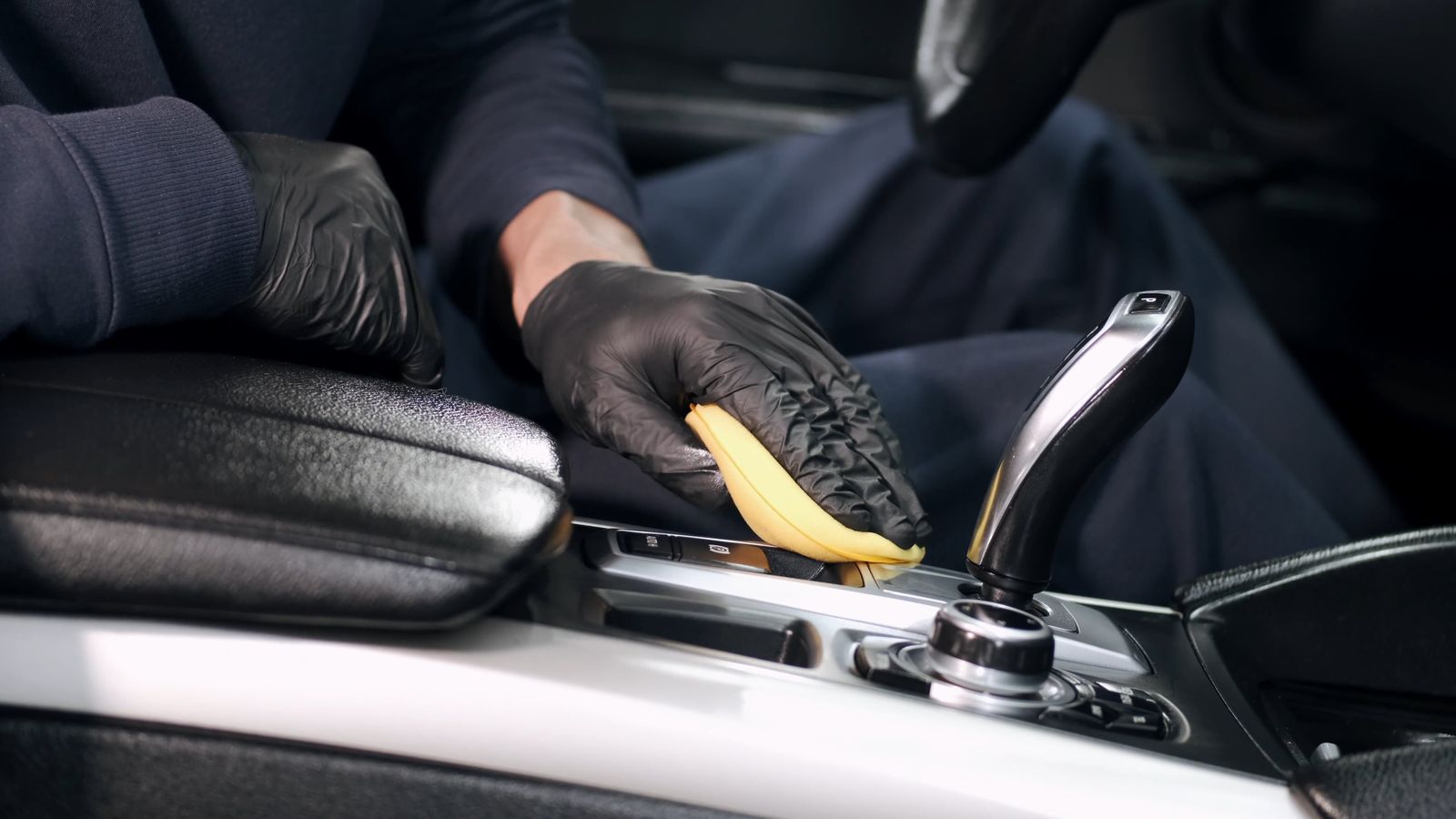 Gloved hands detailing a car's centre console