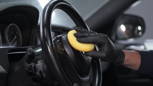 Gloved hand wiping a steering wheel during interior detailing