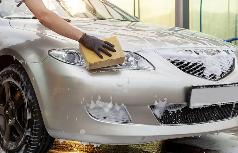 Hand washing a foam-covered car during a mobile detail