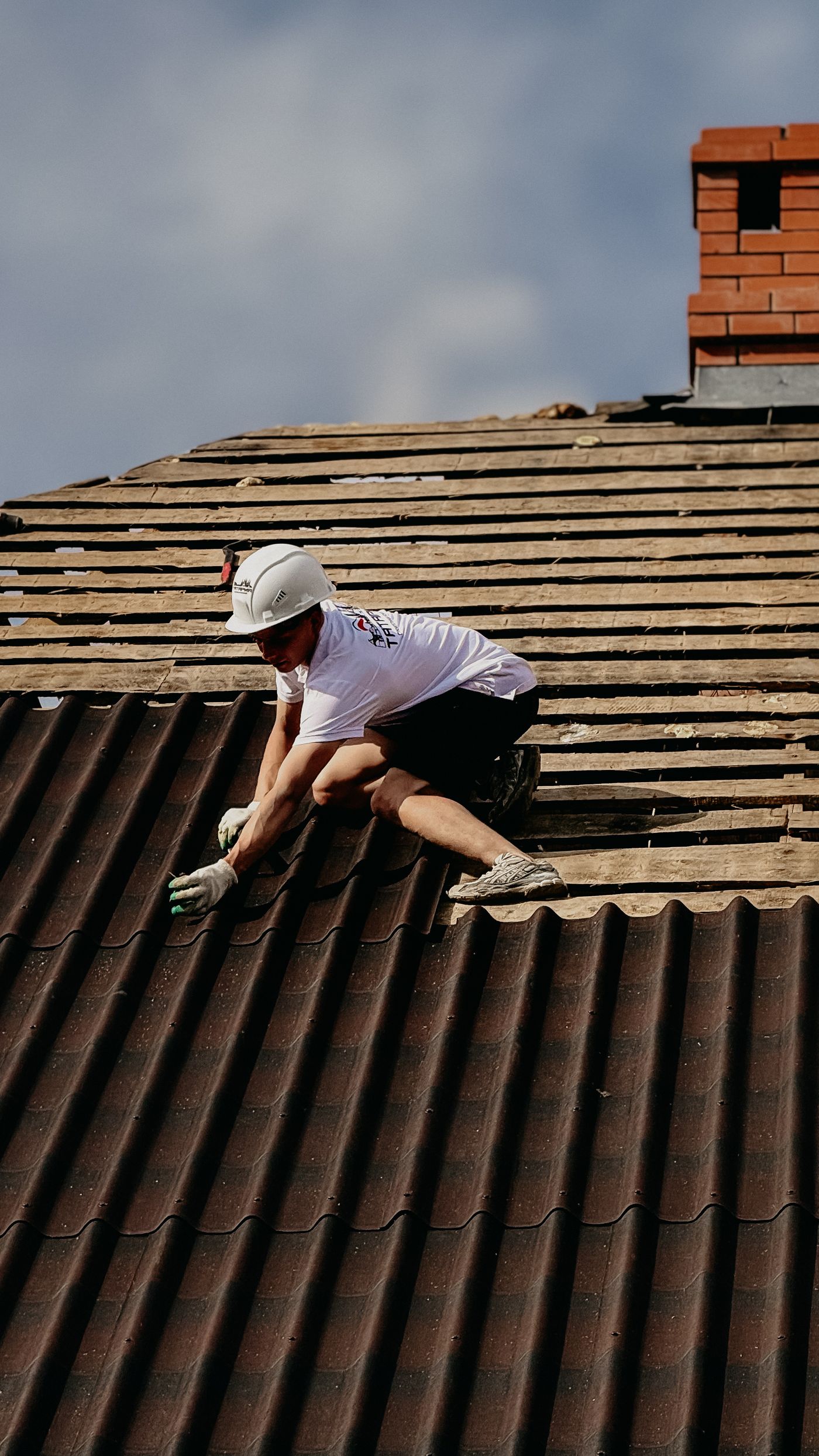 A roofer repairing a roof beneath a chimney stack