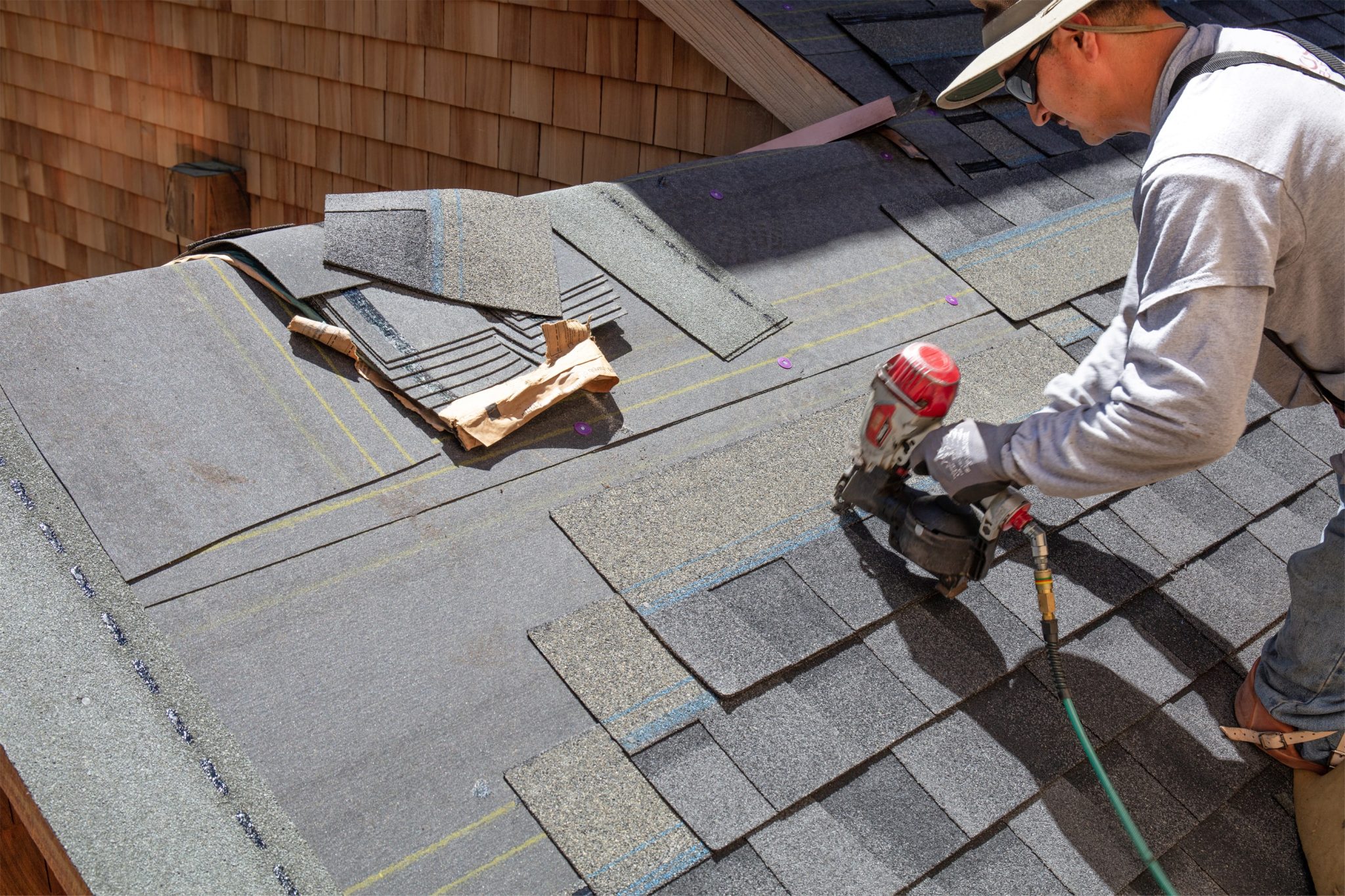 Roofer nailing asphalt shingles