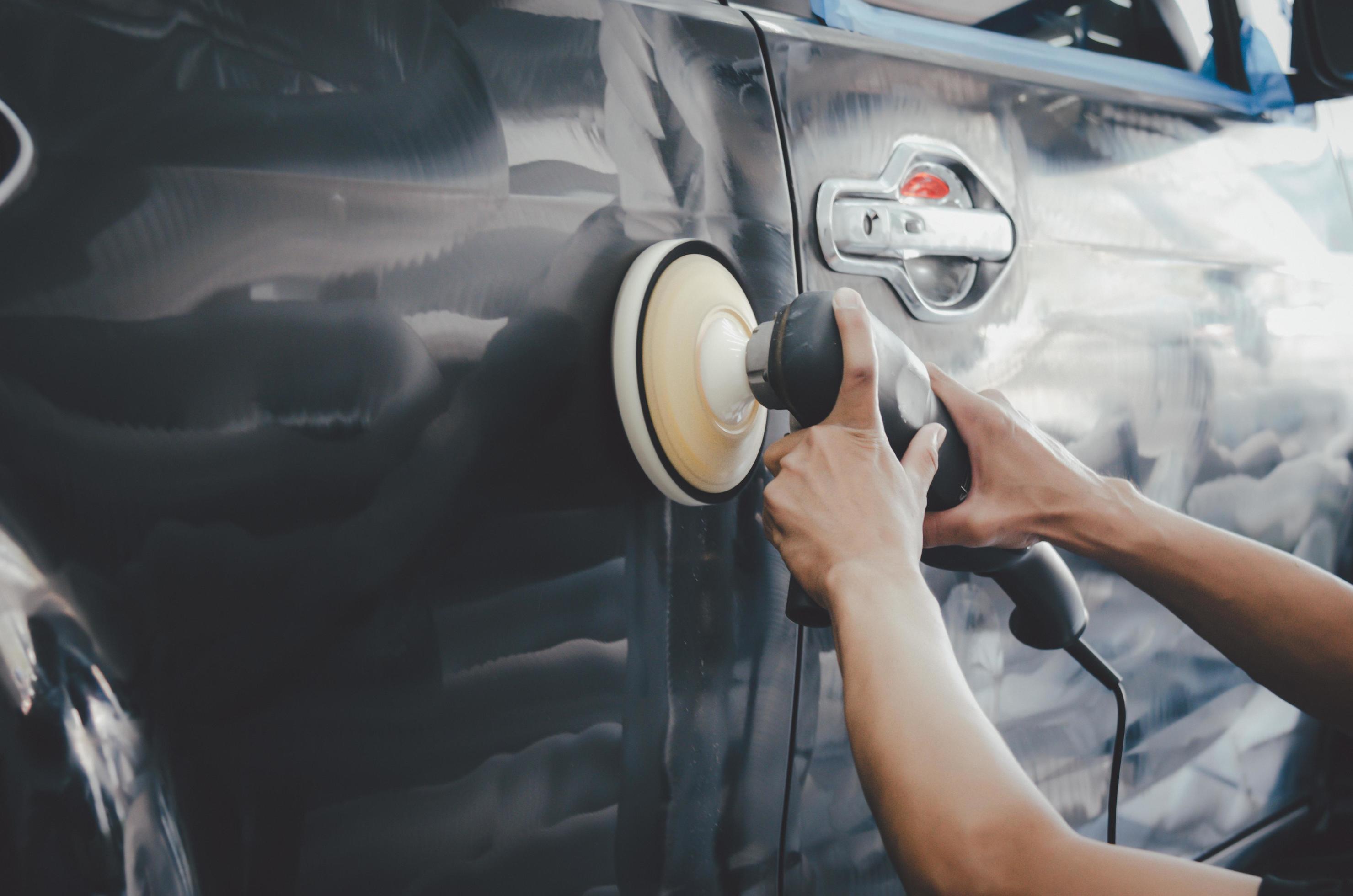 Technician machine-polishing a car