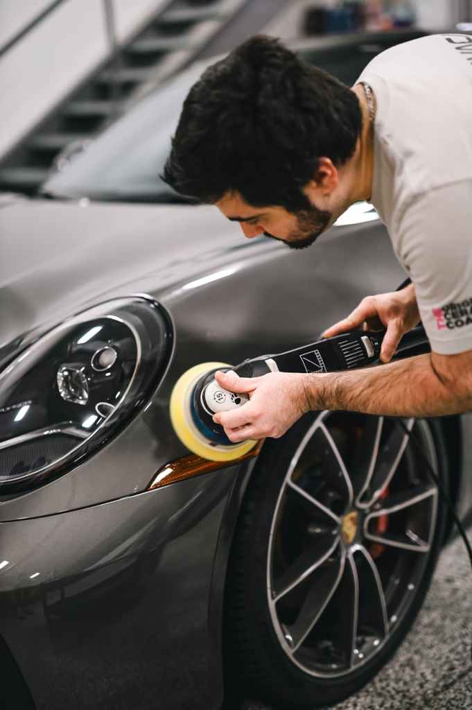 Technician polishing paintwork near the wheel