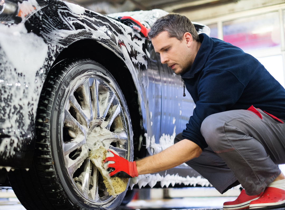 Detailing technician cleaning a wheel on location