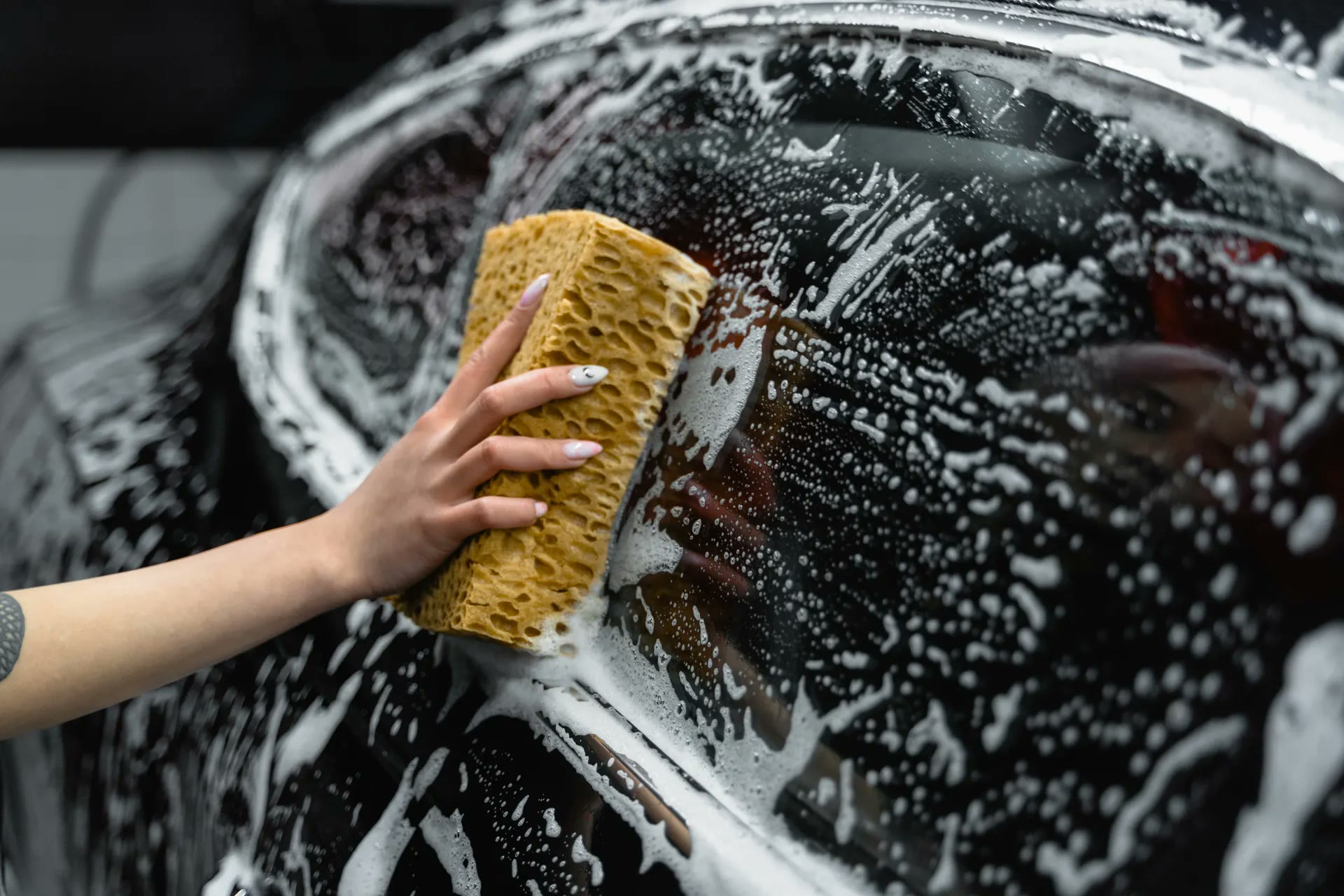 Hand washing a car with foam and sponge (illustrative photo)