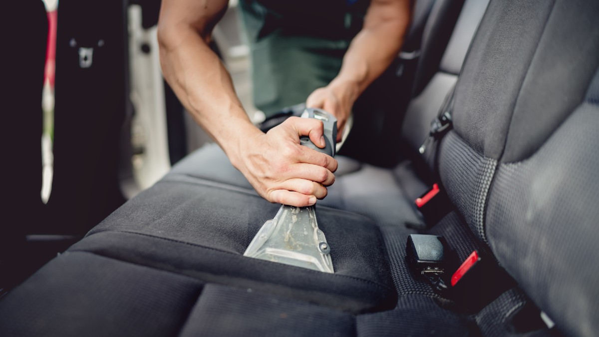 Hot-water extraction cleaning a car seat during an interior detail