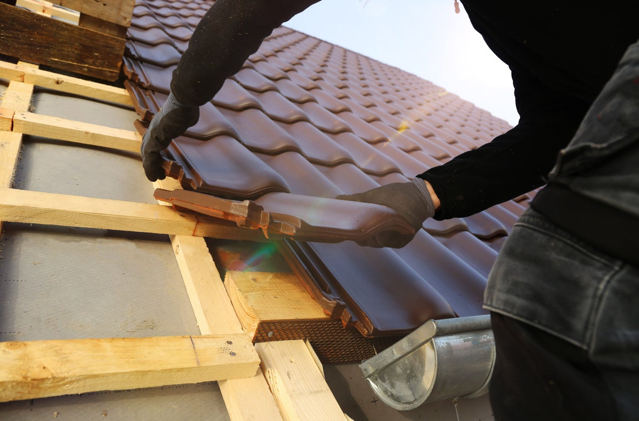 Roofer laying tiles on a pitched roof