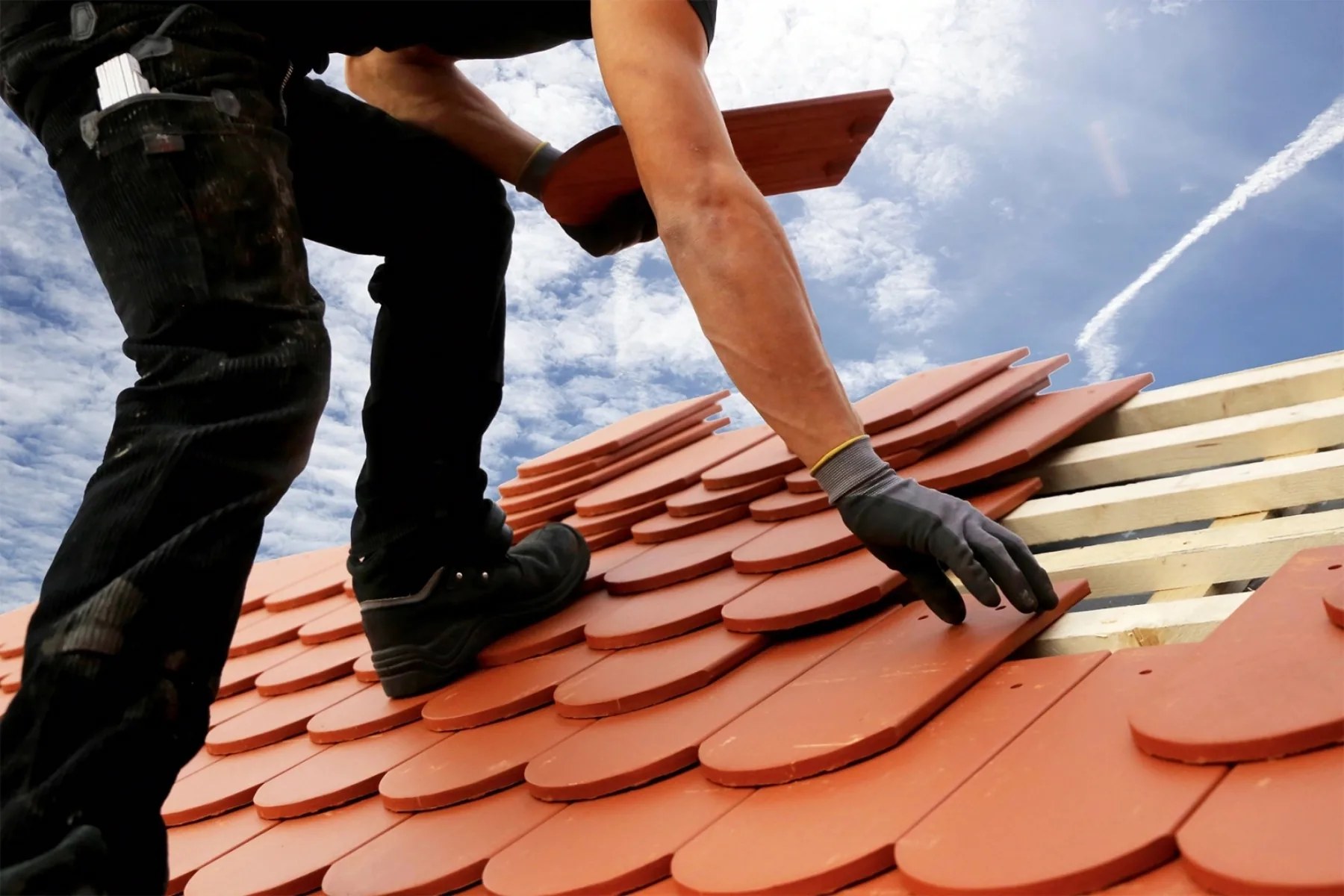 Roofer laying terracotta roof tiles