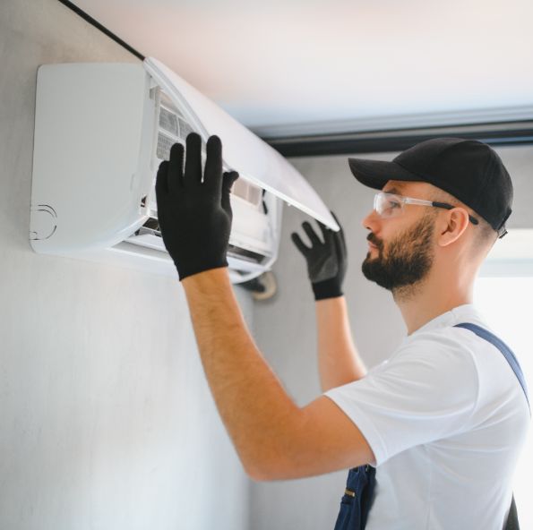 Illustrative photo: technician installing a ductless mini-split indoor unit (stock image, not the actual team)