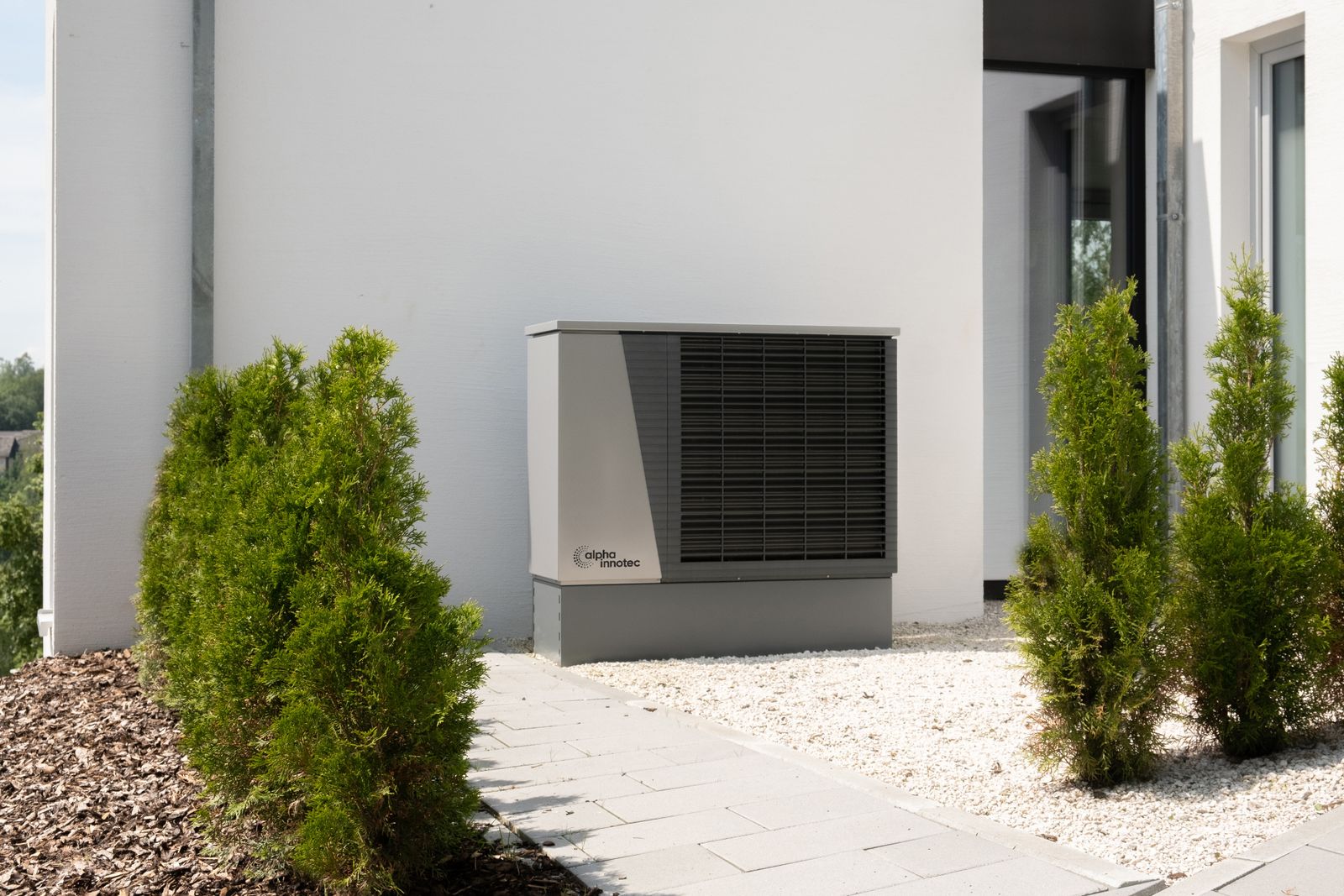 Illustrative photo — air source heat pump beside a modern home