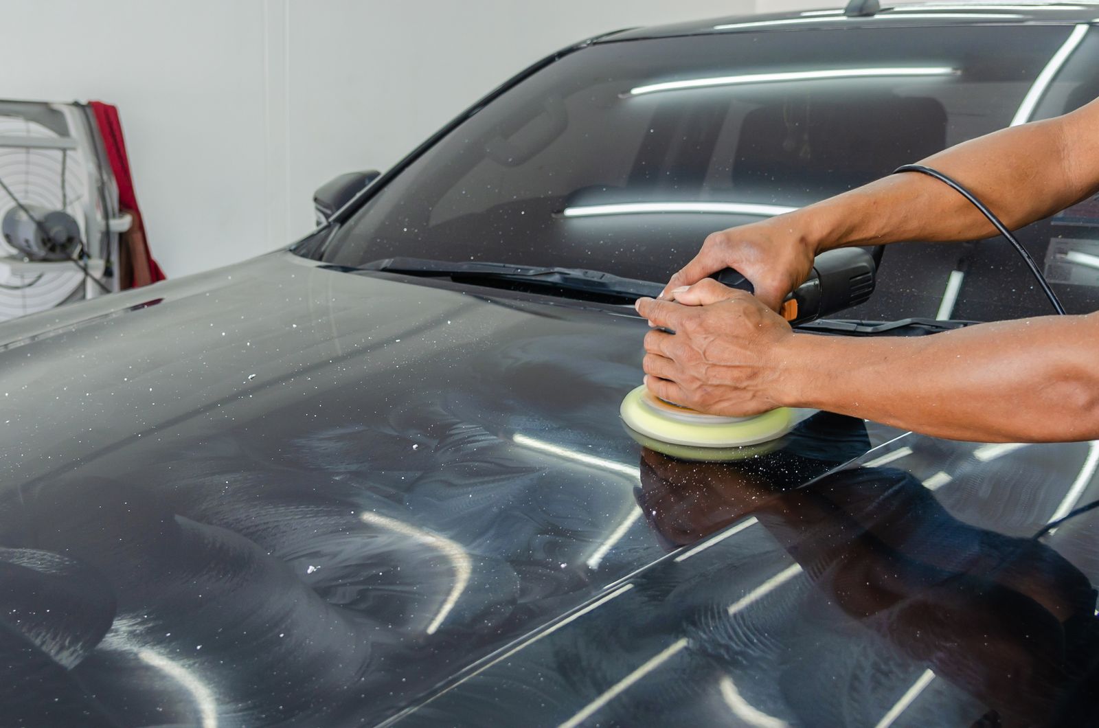 Technician polishing a car during a mobile detailing appointment