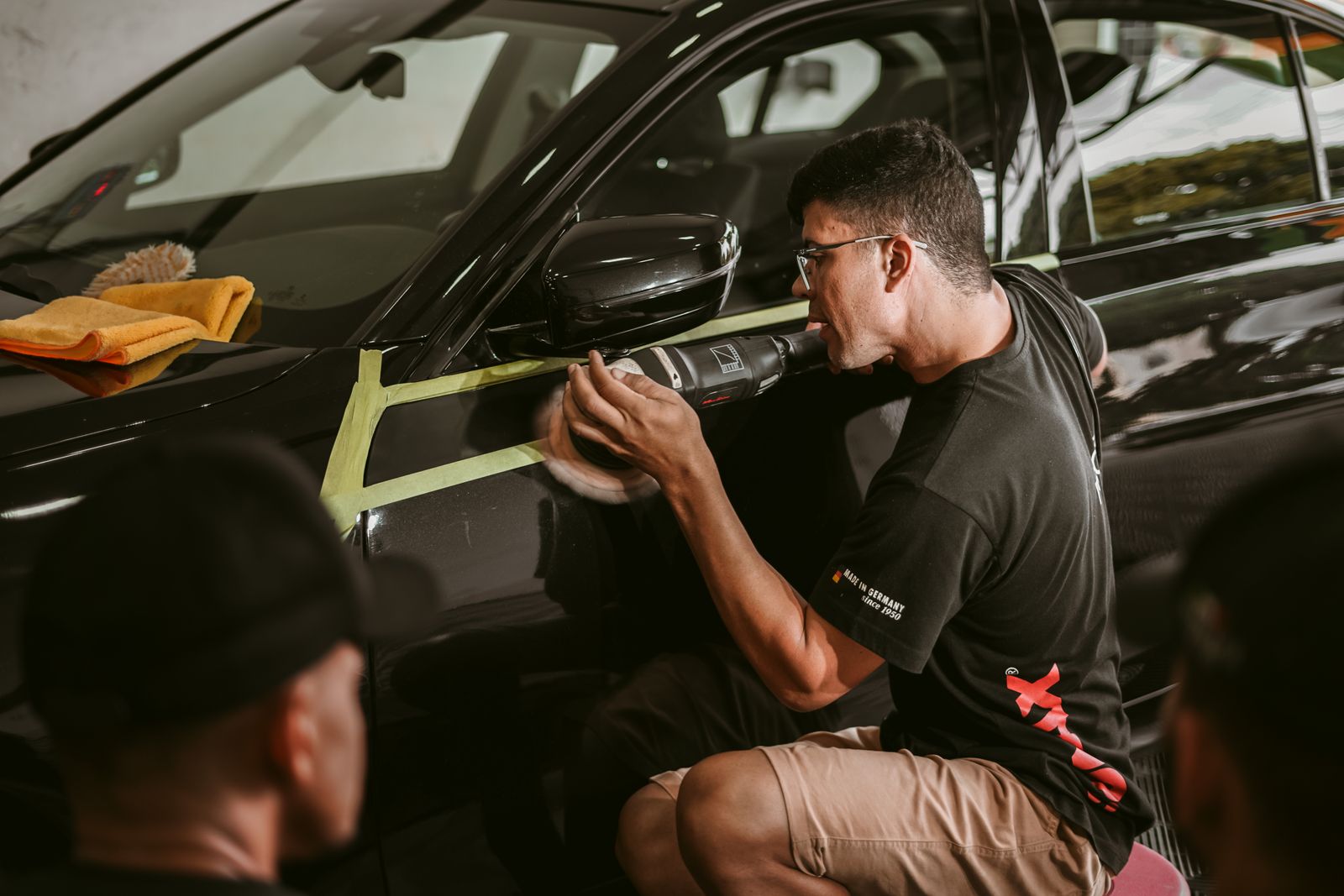 Detailer machine-polishing a car in the workshop