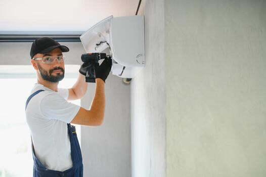 Illustrative photo: technician installing a wall-mounted air conditioning unit