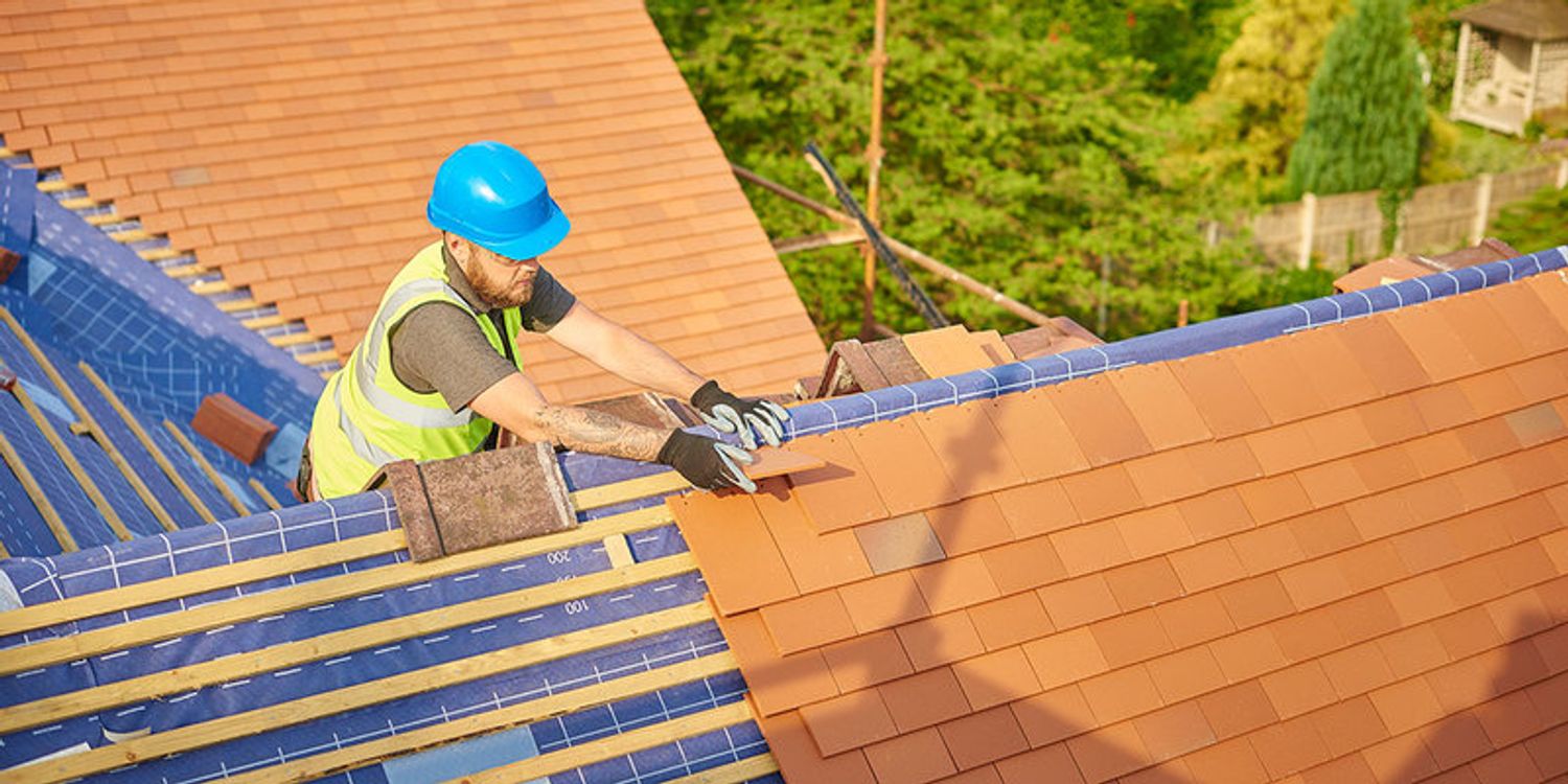 Roofer laying plain tiles on a pitched roof