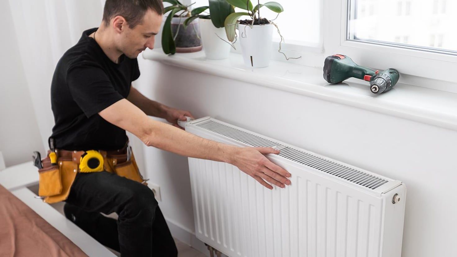 Heating engineer fitting a new radiator in a Manchester home