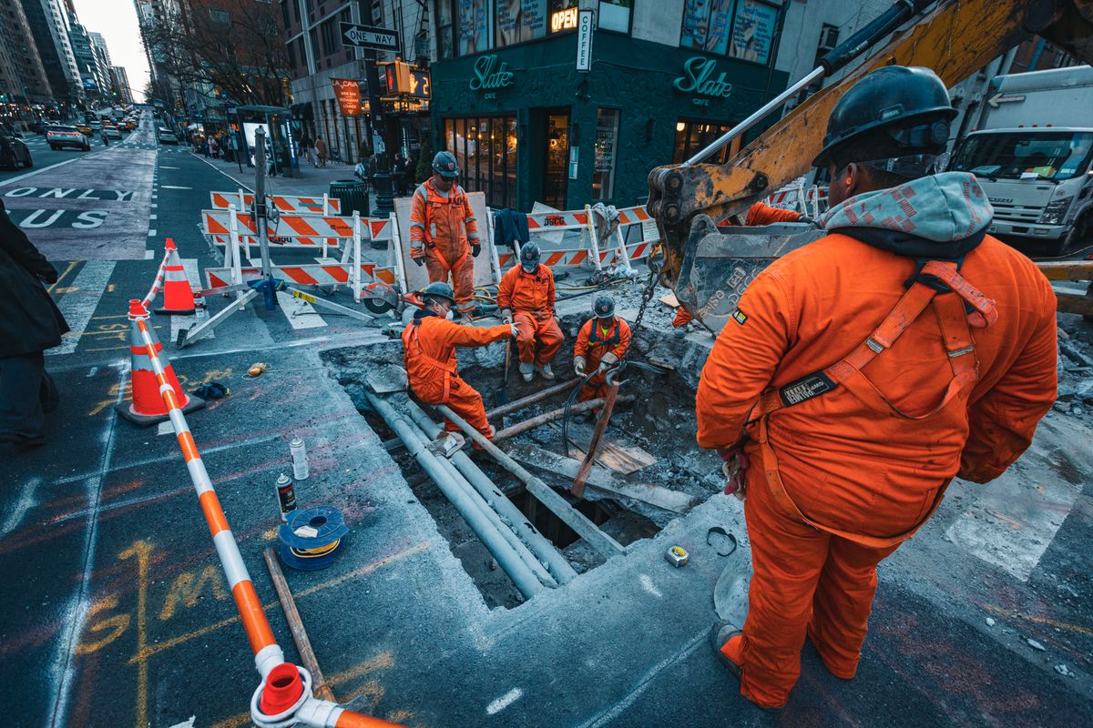 Crew replacing underground pipes at a street excavation