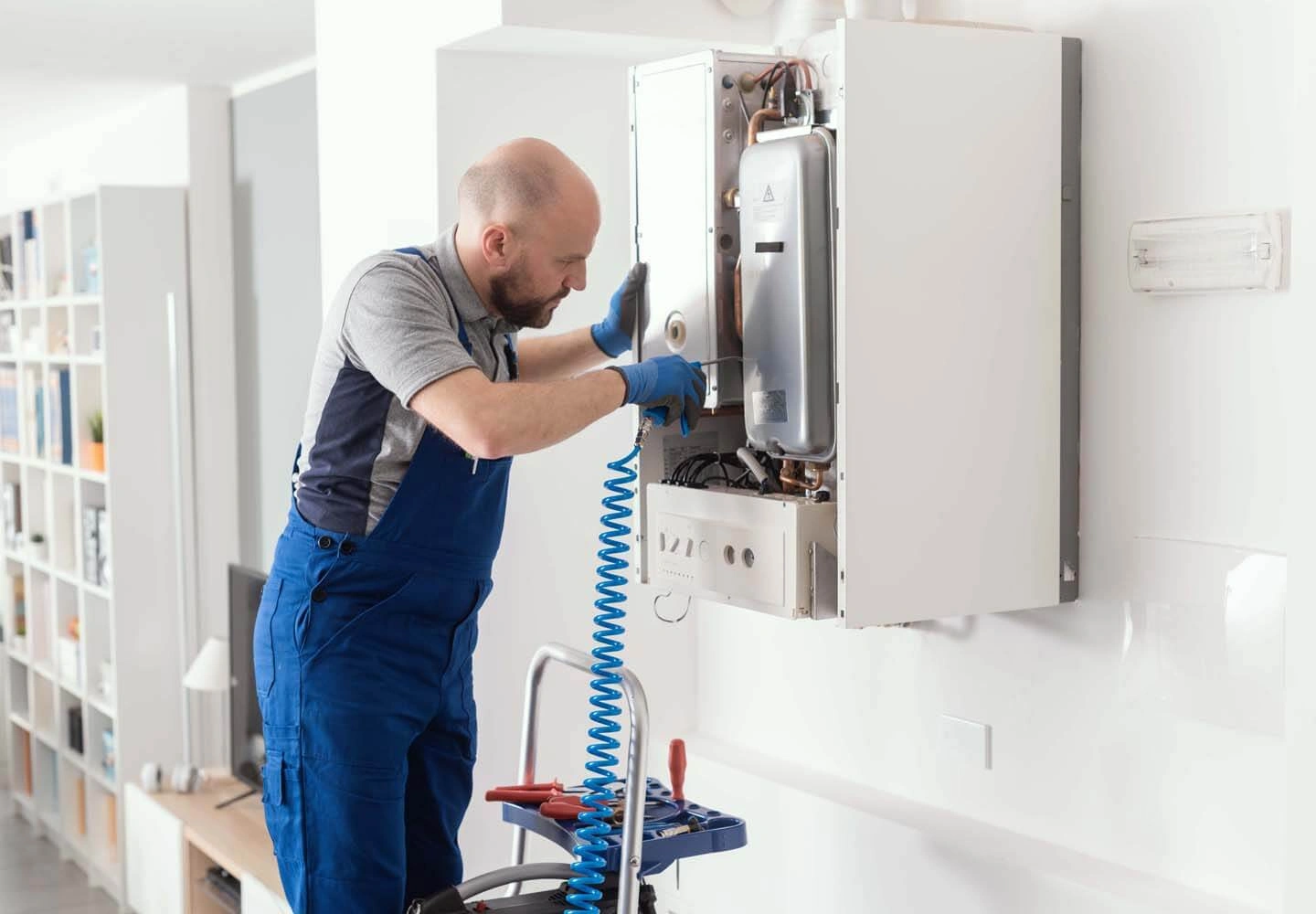 Heating engineer servicing a wall-mounted boiler in a customer's home