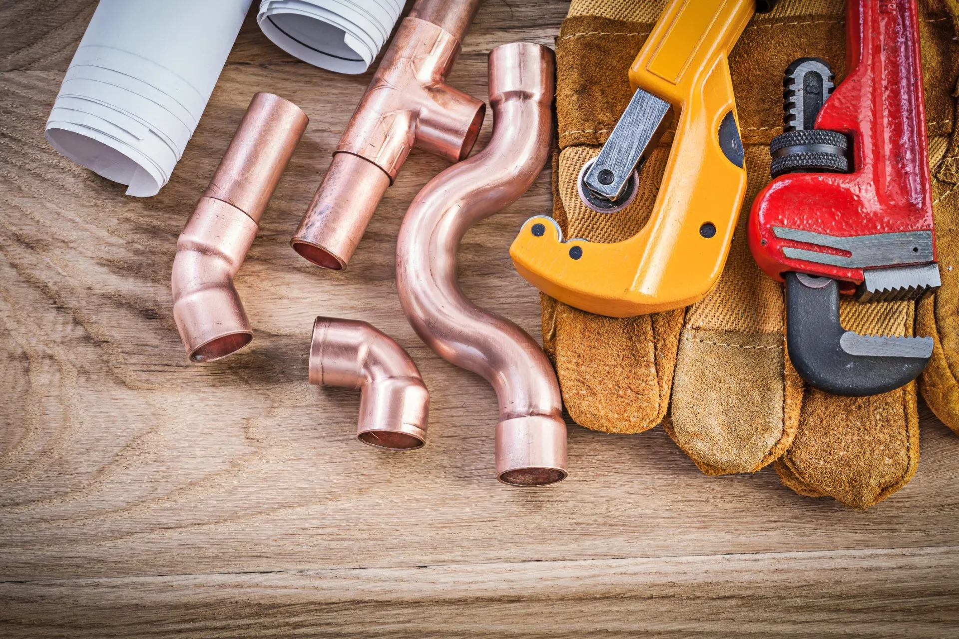 Copper pipes and plumbing tools laid out on a workbench (illustrative concept imagery)