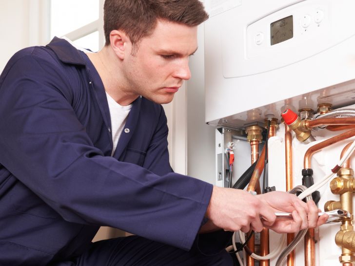Technician working on a wall-hung boiler with copper pipework