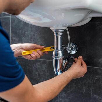 Plumber adjusting pipe under a sink