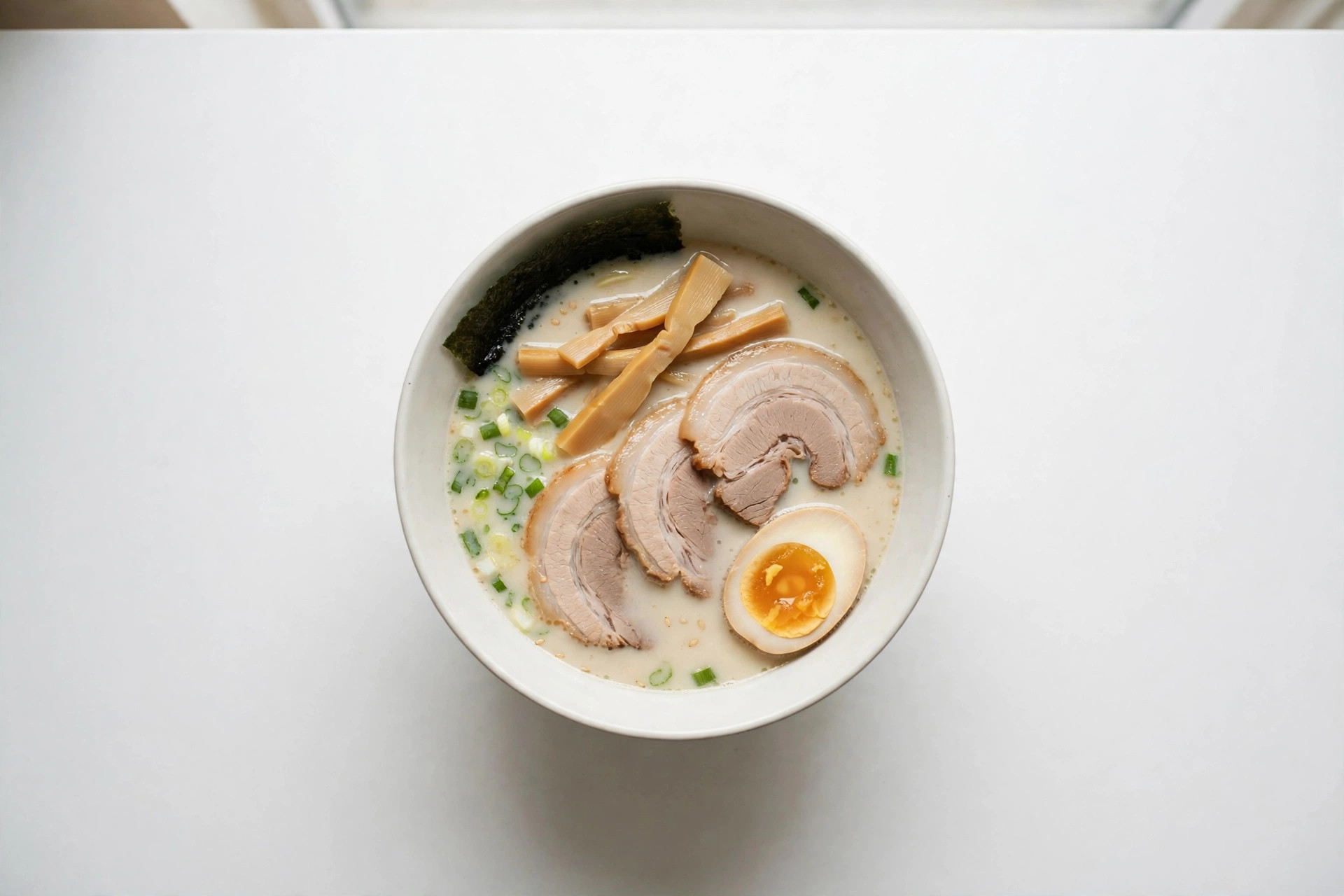 A bowl of tonkotsu ramen with chashu, bamboo shoots, nori and ajitama egg