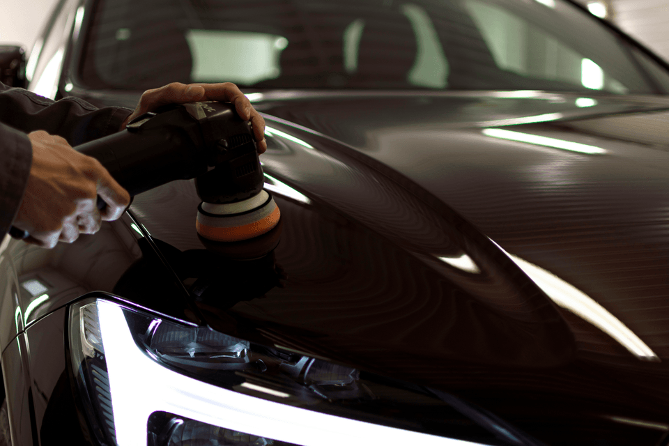 Detailer machine-polishing a car in the shop