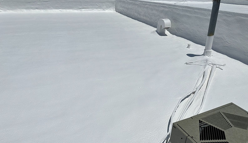 White coated flat roof with parapet and AC unit — illustrative stock photo, not an actual Triumph Roofing job