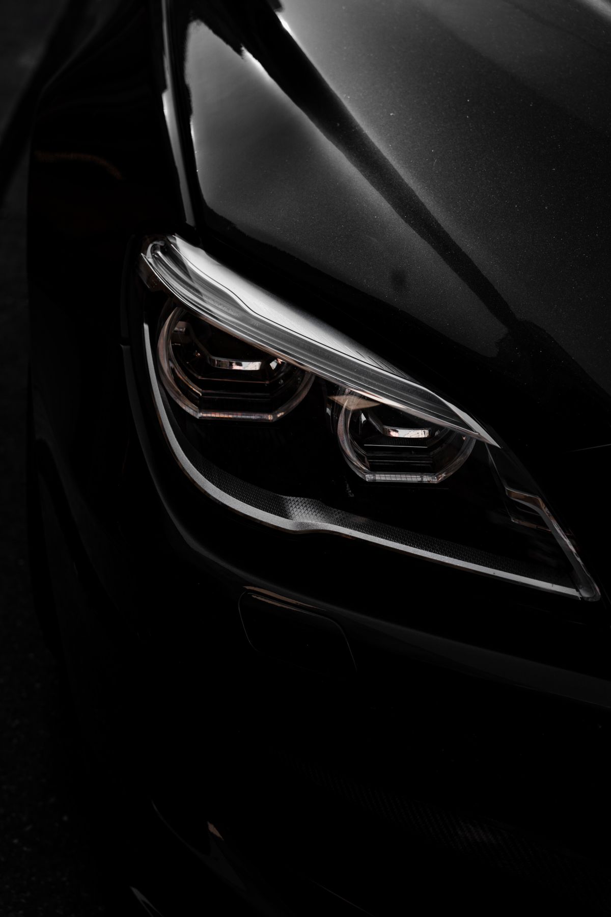 Close-up of a restored glossy black car headlight