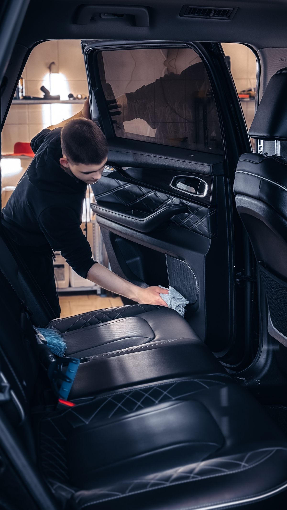 Technician deep-cleaning a car door panel and seat