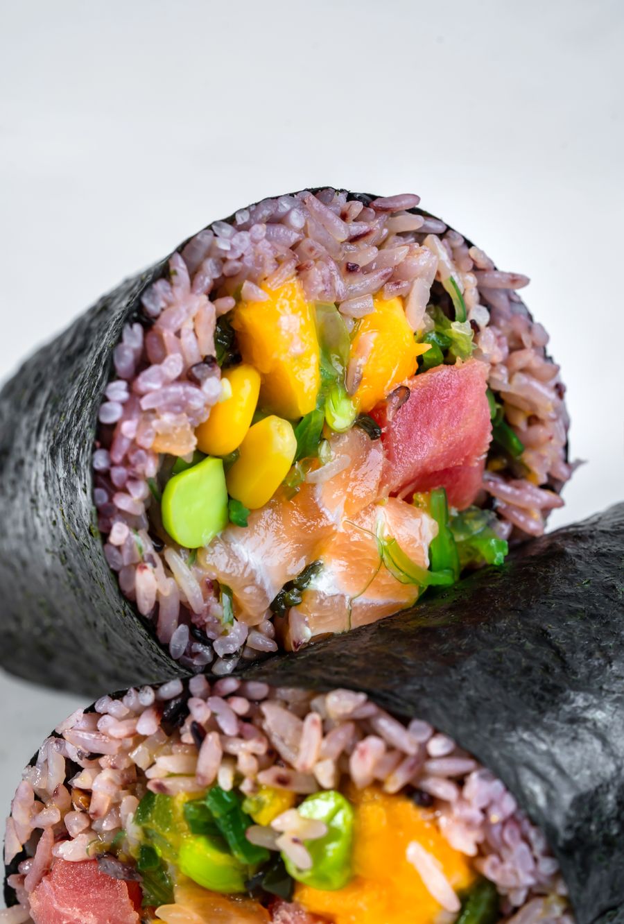 A sushi burrito cut open showing salmon and avocado
